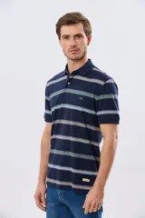 Remera polo de manga corta con diseño a rayas horizontales en tonos azules, celestes, verdes y beiges sobre base azul marino. Presenta cuello camisero con cierre frontal de botones y un pequeño logo bordado en el pecho.