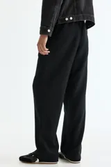 Pantalón negro de corte relajado, confeccionado en mezcla de lino y viscosa, con cintura elástica con cordón de ajuste y bolsillos laterales.