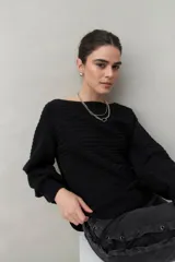 Sweater negro tramado de silueta relajada, con combinación de texturas en el tejido. Presenta mangas abullonadas con puños elastizados, cuello redondo y calce cómodo.