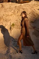 Abrigo largo tipo bata con diseño envolvente y cinturón de cuero. Presenta mangas acolchadas con patrón capitonado, cuerpo de tweed con vivos de cuero y solapa con detalle de corderito.