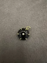 Dije de piedra natural tallada con forma floral, engarzado en metal dorado con una circonia central.