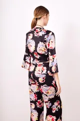 Camisa negra con estampado floral multicolor, escote en V cruzado y mangas acampanadas.