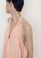 Vestido largo color salmón con escote halter y diseño plisado.