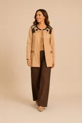 Chaqueta tipo blazer color beige, de corte recto y largo medio. Presenta detalles bordados artesanales en la zona de los hombros y el pecho, con aplicaciones de cuentas y botones decorativos. Posee bolsillos frontales con detalles colgantes y un acabado elegante.