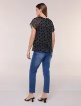 Blusa holgada de gasa negra con estampado geométrico de círculos blancos, cuello redondo fruncido con volados y mangas cortas de corte mariposa.