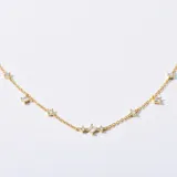 Collar dorado con cadena fina y pequeños dijes de circonitas cúbicas con forma cuadrada y redonda.
