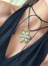 Collar con tiento sintético negro y dije de flor dorada con cristales de vidrio facetados.