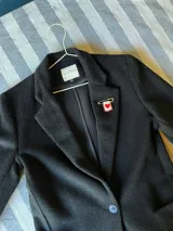 Pin de gancho metálico con dije rectangular bordado que presenta un corazón rojo central atravesado por espadas, decorado con cuentas rojas y doradas en el borde.