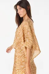 Blusa de lino italiano color blanco, con diseño holgado, escote asimétrico estilo off-shoulder y mangas cortas amplias.