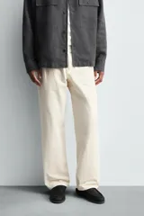 Pantalón de corte regular fit confeccionado en tejido de algodón con textura de espiga. Presenta cintura con pliegues frontales, bolsillos laterales y bolsillos traseros de vivo con botón. Cierre frontal con cremallera y botón.