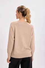 Sweater color beige de tejido de punto, con cuello redondo y mangas largas.