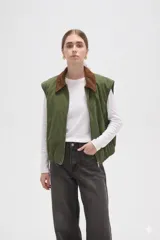 Chaleco de algodón color verde oliva, con cierre frontal y cuello de pana en color marrón. Presenta un diseño holgado con elástico en la cintura.