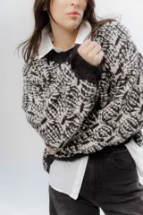 Buzo de tejido grueso con diseño artesanal bicolor en tonos marrón y crema. Presenta cuello redondo y terminaciones en rib en puños y cintura, con un calce relajado.