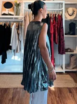 Musculosa de corte amplio y fluido, confeccionada en tejido lamé con acabado metalizado y textura plisada. Presenta un diseño sin mangas con cuello redondo, ideal para eventos nocturnos.