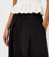 Pantalón de sastrería negro de cintura alta, con pinzas frontales y diseño fluido de perneras anchas.