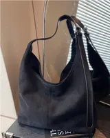 Bolso tipo hobo de material tipo gamuza o nobuk, color marrón camel. Presenta un diseño de silueta suave y caída, con una correa de hombro delgada de cuero liso del mismo tono.