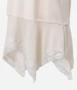 Remera oversized de algodón color beige, de manga corta y cuello redondo, con superposición inferior liviana, bajo asimétrico y aplicación de encaje.