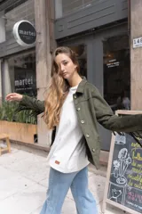 Chaqueta color beige de gamuza sintética con flecos en mangas y canesú, cuello camisero y cierre con botones.