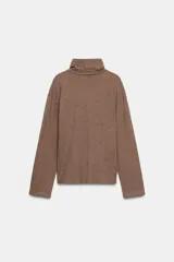 Top de cuello alto y manga larga, confeccionado en tejido de algodón gris melange. Presenta un diseño con frunces laterales ajustados mediante un aplique metálico decorativo.