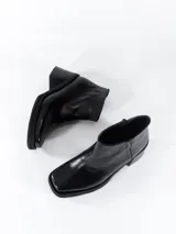 Botas cortas de cuero negro con caña baja y cierre lateral. Presentan puntera cuadrada y taco ancho.
