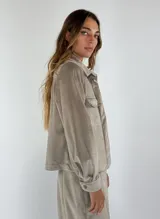 Chaqueta azul marino de terciopelo con cuello camisero, cierre frontal con botones, dos bolsillos de parche con solapa y mangas largas con puños abotonados.