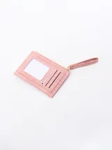 Billetera blanca con textura de cocodrilo, cierre de cremallera superior y un bolsillo frontal con solapa y botón a presión. Incluye una correa lateral para la muñeca.