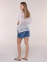 Poncho de tejido calado color beige, con mangas cortas, aberturas laterales y lazos ajustables en el cuello. Modelo Do Everything In Love.