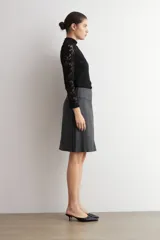 Falda de corte recto y largo midi, confeccionada en eco cuero negro con acabado mate y costuras verticales visibles.