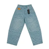 Pantalón de mezclilla de Nude Project con corte baggy, color azul claro con patrón estampado de flores en relieve y apliques de tachas metálicas en las piernas.