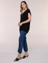 Blusa negra de tejido de punto fino con hilos de lúrex brillante, escote redondo amplio, mangas cortas con hombros caídos y silueta semi holgada.