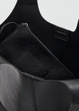 Bolso tipo hobo color negro, confeccionado en poliuretano con textura granulada, asa de hombro integrada y diseño amplio y flexible.