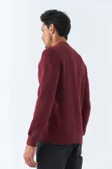 Buzo de felpa color bordó con cuello redondo, mangas largas y corte regular. Presenta un estampado con la frase "Think out of the box" en el frente y logo de la marca bordado.