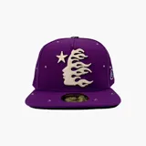 Gorra tipo fitted color violeta con diseño bordado frontal que representa un perfil humano con llamas y una estrella. Presenta detalles de tachas metálicas incrustadas en la corona y la visera.