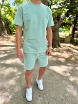 Conjunto deportivo para hombre compuesto por una remera de manga corta con cuello redondo y un short con cordón ajustable en la cintura, ambos en color verde menta.