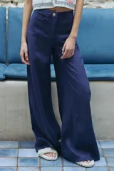 Pantalón de lino corte wide leg, de tiro alto y diseño de cinco bolsillos. Cuenta con cierre frontal y botón metálico personalizado.