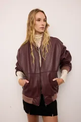 Campera bomber de cuero vacuno en color bordó, con diseño oversized y corte bombé. Presenta cierre frontal, bolsillos laterales y terminaciones de puños, cuello y pretina en tejido de algodón acanalado a tono.
