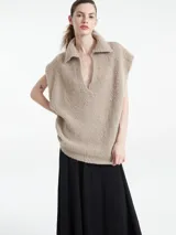Poncho de punto con textura, color beige, con cuello polo y escote en V profundo. Diseño sin mangas y corte holgado.