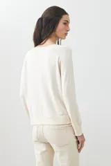 Sweater básico de tejido de punto color beige, de corte recto y mangas largas.