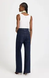 Jean de corte recto y tiro alto, confeccionado en denim azul oscuro. Presenta costuras verticales frontales que estilizan la silueta, cintura estructurada con trabillas, bolsillos funcionales y cierre frontal con botón y cremallera.