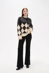Sweater de tejido jacquard con diseño de rombos en color negro y beige, de corte holgado, cuello redondo y mangas largas con puños anchos.