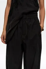 Pantalón jogger negro confeccionado en mezcla de lyocell y algodón, de tiro medio con bolsillos laterales y bajos ajustables mediante cordones elásticos con stoppers.