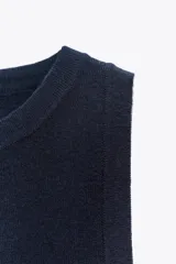 Top de punto color amarillo mostaza, con cuello redondo y manga sisa. Acabados en rib a tono.