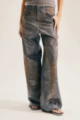 Jean de corte amplio en toda la pierna, con textura desgastada y efecto animal print de serpiente o cocodrilo en tonos gris y terracota.