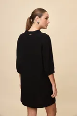 Vestido corto negro de silueta relajada, con escote en V y mangas 3/4 levemente abullonadas.