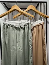 Pantalón deportivo color verde agua, de corte holgado, con cintura elástica y tres rayas blancas verticales a los costados.