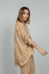 Camisa de manga larga color rosado con estampado de flores anaranjadas y blancas.
