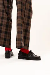 Zapato náutico de cuero color chocolate con horma cuadrada. Presenta detalles de pasamanería en cuero descarne que recorren el frente y los laterales, cordones frontales y suela plana con pequeño taco.