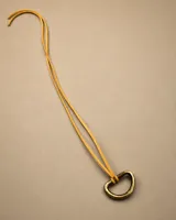 Choker de cuero amarillo con dije metálico de bronce en forma geométrica irregular.