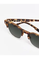 Lentes de sol Tiwi modelo Lucien con armazón bicolor, parte superior en estampado carey y parte inferior transparente. Cuentan con cristales oscuros y detalles metálicos en las esquinas.