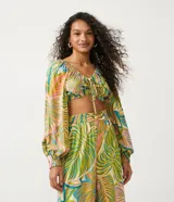 Blusa cropped de viscosa con estampado tropical de follaje, escote en V con lazo, mangas largas con elástico y bajo ajustable.